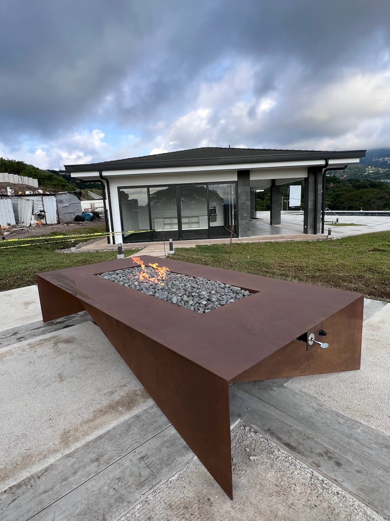 Pieza sculptural custom FIREPITSCR en acero corten con pliegues angulares y quemador rectangular sobre lava.