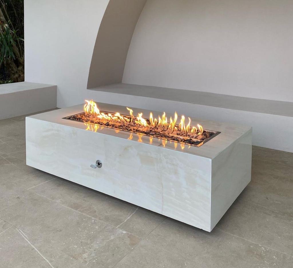 Fire table rectangular FIREPITSCR de perfil bajo, superficie clara tipo piedra y quemador lineal activo.