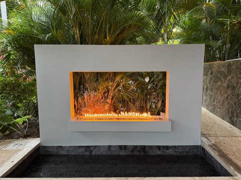 Fireplace lineal FIREPITSCR en jardín — muro blanco con hornacina a fuego vista y espejo de agua.